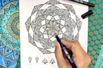 The Création Mandala template from März is refined with a Tombow MONO drawing pen fineliner. The symmetrical pattern consists of filigree ornaments and leaf shapes. Various decorative elements can be seen at the bottom of the mandala.